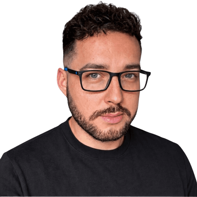 Sean, who runs ASD Built: a man with short dark curly hair, a beard and black-framed glasses, wearing a black T-shirt, photographed against a plain white background.